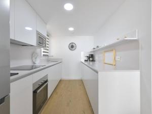 a white kitchen with white cabinets and a wooden floor at Apartamento de lujo vista mar en Torrox Costa in Torrox Costa