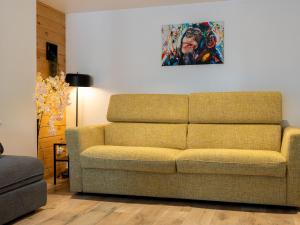 a couch in a living room with a painting on the wall at Ô17 Séjour wellness avec bain nordique à 5 min de Namur in Namur
