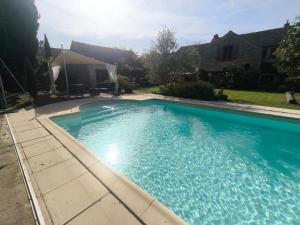 a large blue swimming pool in a yard at La Closerie DAUVILLIERS in Roinville