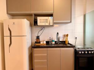 a kitchen with a white refrigerator and a microwave at Apartamento Unicco 25, next to USP in São Carlos