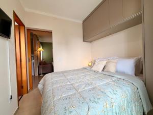 a bedroom with a large bed with a blue comforter at Apartamento Unicco 25, next to USP in São Carlos