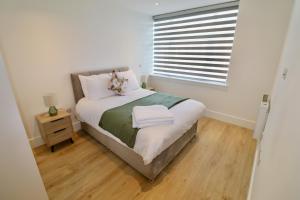 a small bedroom with a bed and a window at Chertsey Modern 2-Bed Flat with Parking in Chertsey