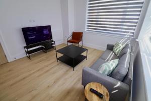 a living room with a couch and a television at Chertsey Modern 2-Bed Flat with Parking in Chertsey +4 photos