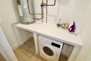 a laundry room with a washing machine on a counter at Chertsey Modern 2-Bed Flat with Parking in Chertsey