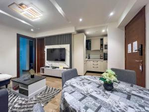 a living room with a dining room table and a kitchen at Solaris Executive Suites Osu Pool Gym in Accra