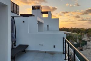 a white house with a bench on a balcony at 2bd Tulum Country ClubPGA golfMid termgrocery in Akumal