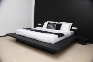 1 cama con almohadas blancas y negras en una plataforma negra en Ariya Tissa en Tissamaharama