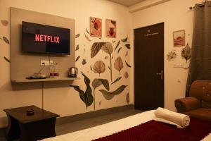 a room with a bed and a tv on a wall at Amara Inn by Sandane Homes Near Expo mart and Pari Chowk in Greater Noida