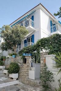 a white house with blue windows and trees at LITO STUDIOS APARTMENTS in Pythagoreio