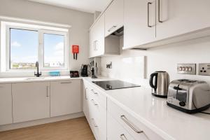 a white kitchen with white cabinets and a window at The Maltings in Portlaoise +10 photos