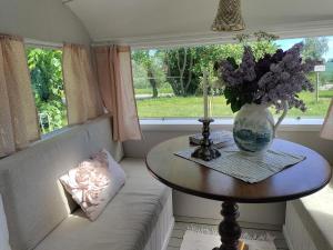 a vase of flowers sitting on a table in front of a window at The running Rabbit caravan in Ystad