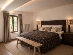 a bedroom with a large bed and a wooden bench at Villa Flora 1909 - Private Alpine Residence in Grindelwald