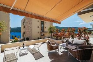 a patio with chairs and a couch and a table at Boho Apartment with Sea View & Pool in Baošići