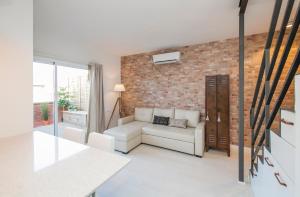 バルセロナにあるBARCELONA PENTHOUSE Private Terrace Sustainable Stay Keyless Accessの白いソファとレンガの壁が備わるリビングルーム