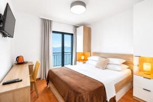 a bedroom with a bed with a desk and a window at Galeb Bed and Breakfast in Baćina