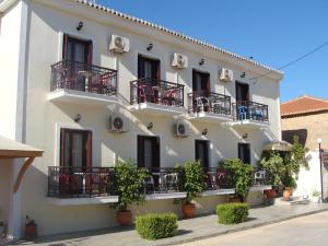 a white building with balconies and potted plants at Hotel Aris in Methoni