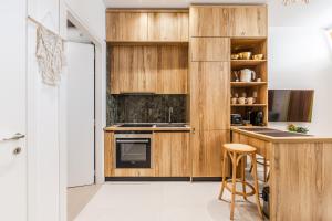 a kitchen with wooden cabinets and a counter with a stool at NooN Properties Santorini by PikHost in Palasë