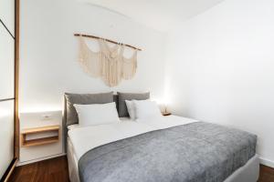 a bedroom with a bed with white sheets and a window at Boho Apartment with Sea View & Pool in Baošići