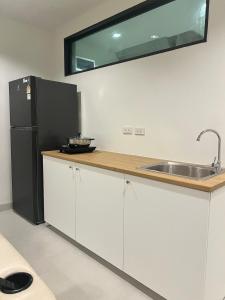 a kitchen with a sink and a black refrigerator at 2 Bed & 2 Bath Suite, 5th floor in Ban Bang Toei (1)