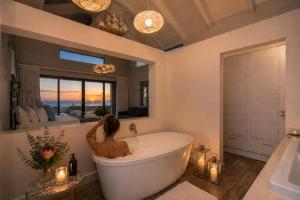 a woman sitting in a bath tub in a bathroom at Peninsula Villa - Romansbaai in Gansbaai