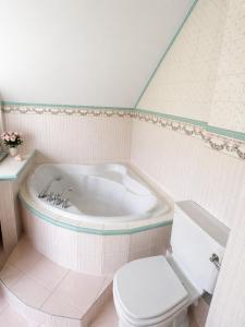 a white bathroom with a tub and a toilet at Prestige Garden Villa - Cracow in Krakow +11 photos