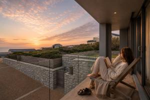 a woman sitting in a chair on a balcony watching the sunset at Peninsula Villa - Romansbaai in Gansbaai +58 photos