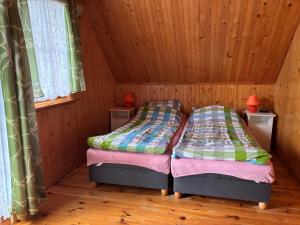 two beds in a room with wooden walls at Alga in Mrzeżyno