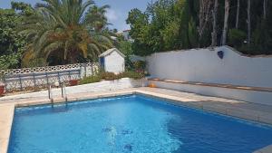 a blue swimming pool with a white fence and trees at La Font Moraira in Moraira