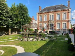 a large brick house with a garden in front of it at La Demeure De Charme in Troyes