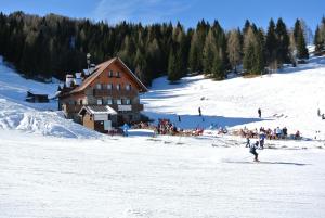 a group of people in the snow near a ski lodge at Albergo Al Cocul in Sùtrio