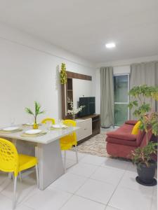 a living room with a table and yellow chairs at Apto Tropical - Enseadas dos Corais in Cabo de Santo Agostinho