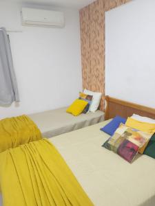 a room with two beds with yellow sheets and a window at Apto Tropical - Enseadas dos Corais in Cabo de Santo Agostinho