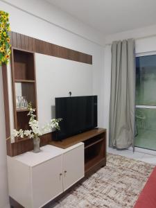 a living room with a flat screen tv on a cabinet at Apto Tropical - Enseadas dos Corais in Cabo de Santo Agostinho