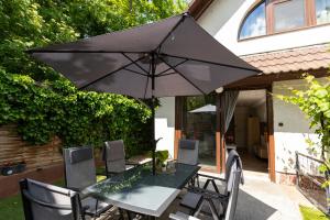 a table and chairs with an umbrella on a patio at Sári Apartman in Balatonalmádi