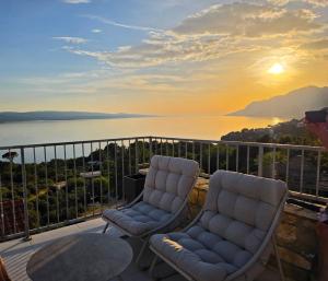 two chairs and a table on a balcony with the sunset at Apartments Jelinek in Brela