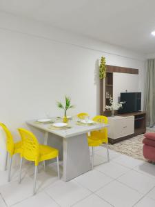 a dining room with a white table and yellow chairs at Apto Tropical - Enseadas dos Corais in Cabo de Santo Agostinho +25 photos