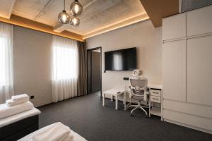 a hotel room with a desk and a tv at Olive INN Berlin in Berlin