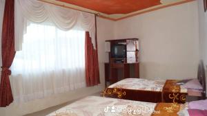 a bedroom with a bed and a tv and a window at Hostal Juyanis in Otavalo
