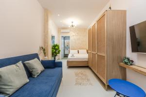 a living room with a blue couch and a bed at NooN Properties Santorini by PikHost in Palasë