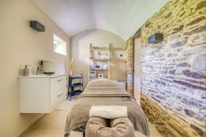 a bedroom with two beds and a stone wall at Le Manoir de Kerbot in Sarzeau
