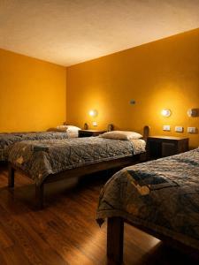 a hotel room with two beds and yellow walls at Hostal Café Tiana in Latacunga