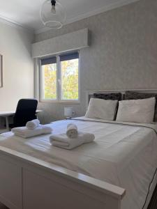 a bedroom with a large white bed with towels on it at Quarto confortável in Amadora