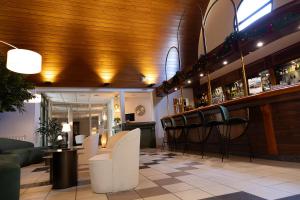 a bar with white chairs and a wooden ceiling at The Originals City, Le Patio Hôtel, Cholet Nord in Beaupréau