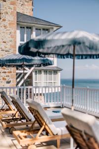 a group of lounge chairs and an umbrella on a deck at Les Bassans - Fontenille Collection in Perros-Guirec