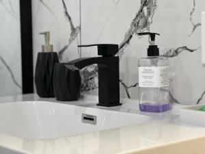 a bathroom sink with a bottle of soap and a mirror at Appartement 1 - OUEST in Rimouski +35 photos