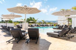 a group of chairs and umbrellas next to a pool at Oros Paradise Hotel in Pastida