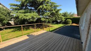 a porch with a wooden deck and a fence at Gite Les Pivoines in Saint-Robert