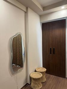 a mirror on a wall next to two stools at CasaVerve stay in Greater Noida