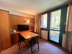 a room with a desk and a table and a window at Monolocale Des Alpes 204 in Madonna di Campiglio
