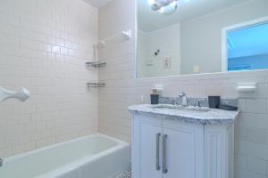 a white bathroom with a tub and a sink and a mirror at Arlington Suite in Arlington +13 photos